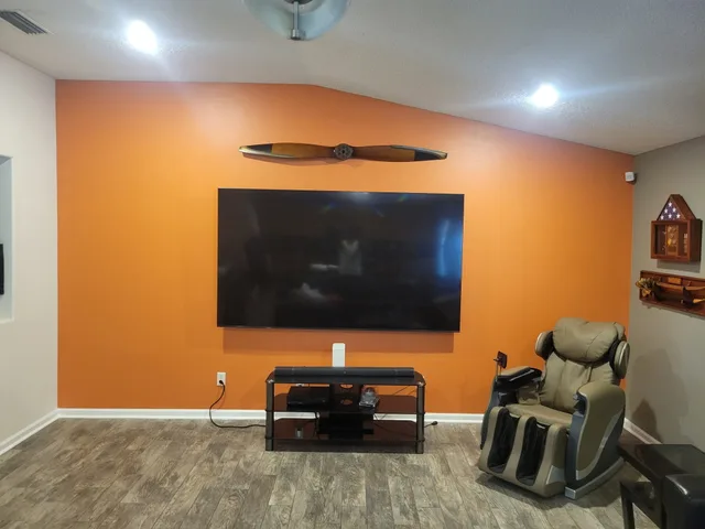 A media room accent wall in Jacksonville freshly painted burnt orange behind a mounted TV