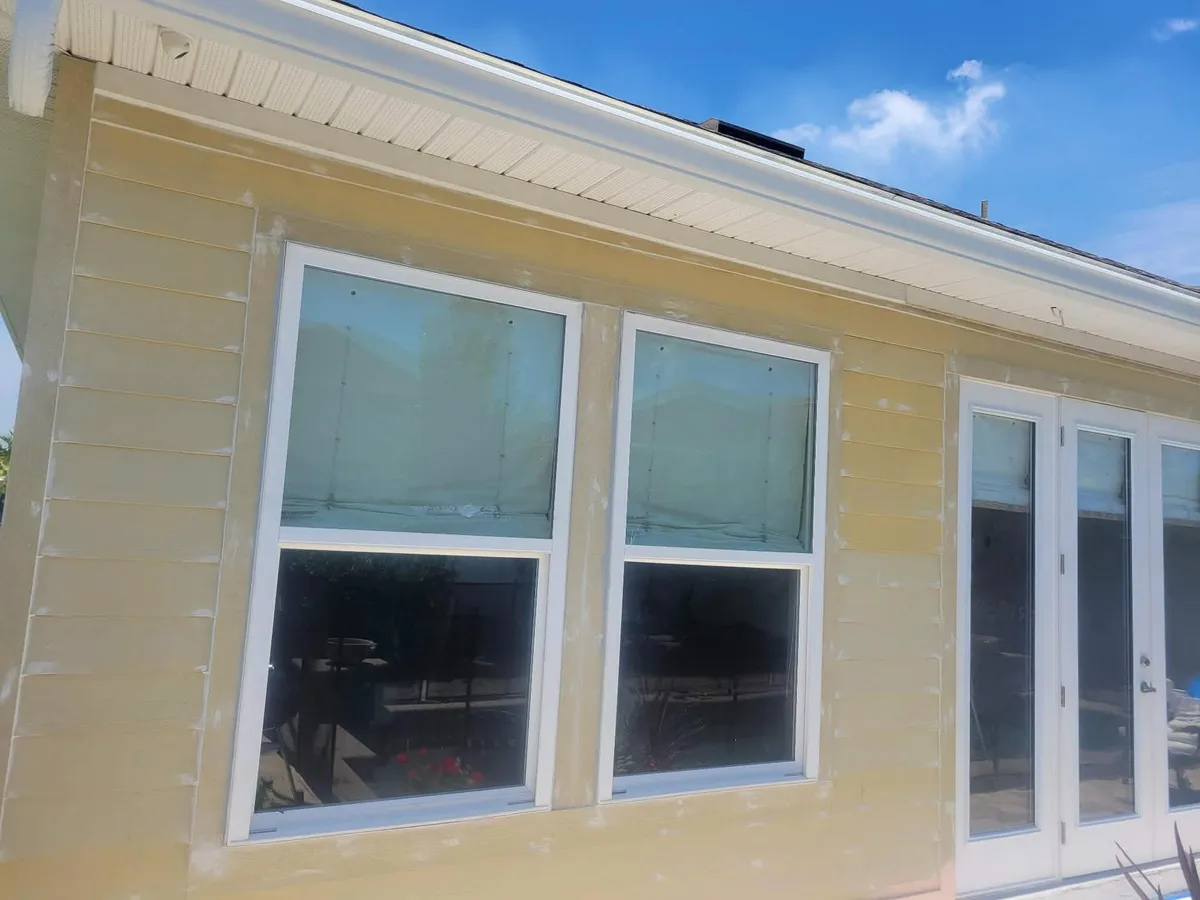 Faded yellow lap siding with patched and sanded spots before repainting