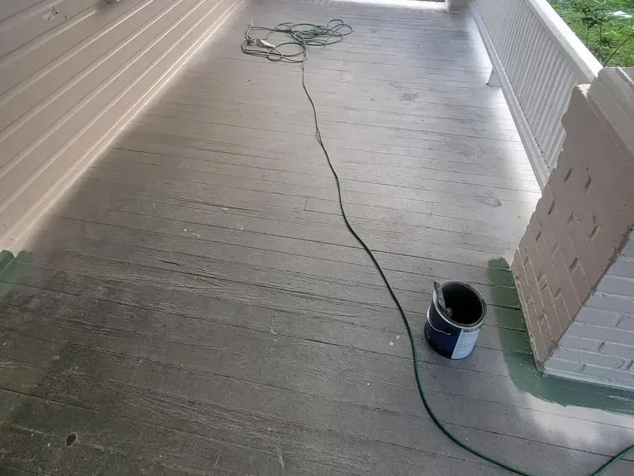 Bare, worn gray wood porch decking with peeling finish before painting